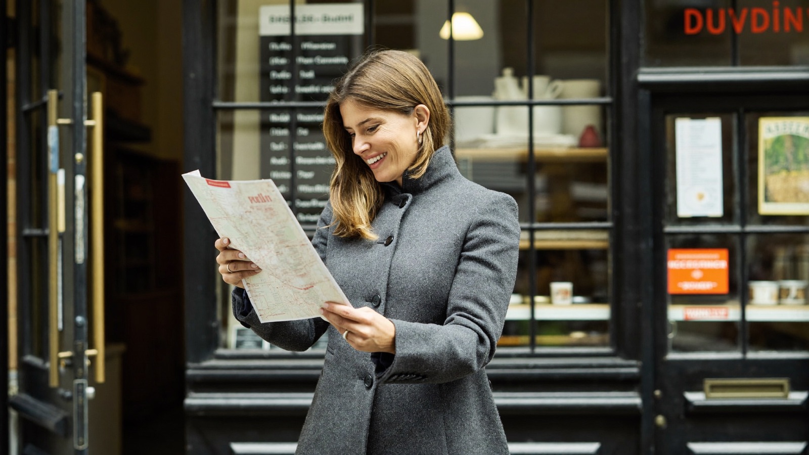 A shop owner checking her business listing on Google Maps on a phone outside her store